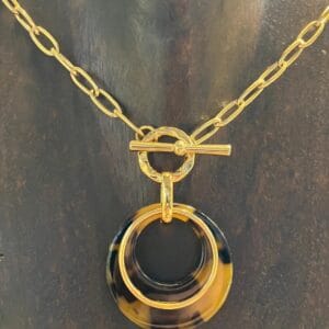 collar artesanal en acero dorado sobre expositor oscuro