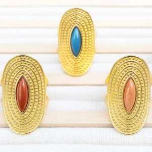 Cinco anillos París de acero inoxidable con piedras en turquesa, terracota, azul verdoso, petróleo y beige, sobre fondo texturizado