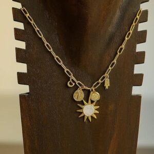 Collar Sol en acero inoxidable dorado con colgantes de sol, mano y discos sobre expositor de madera oscuro