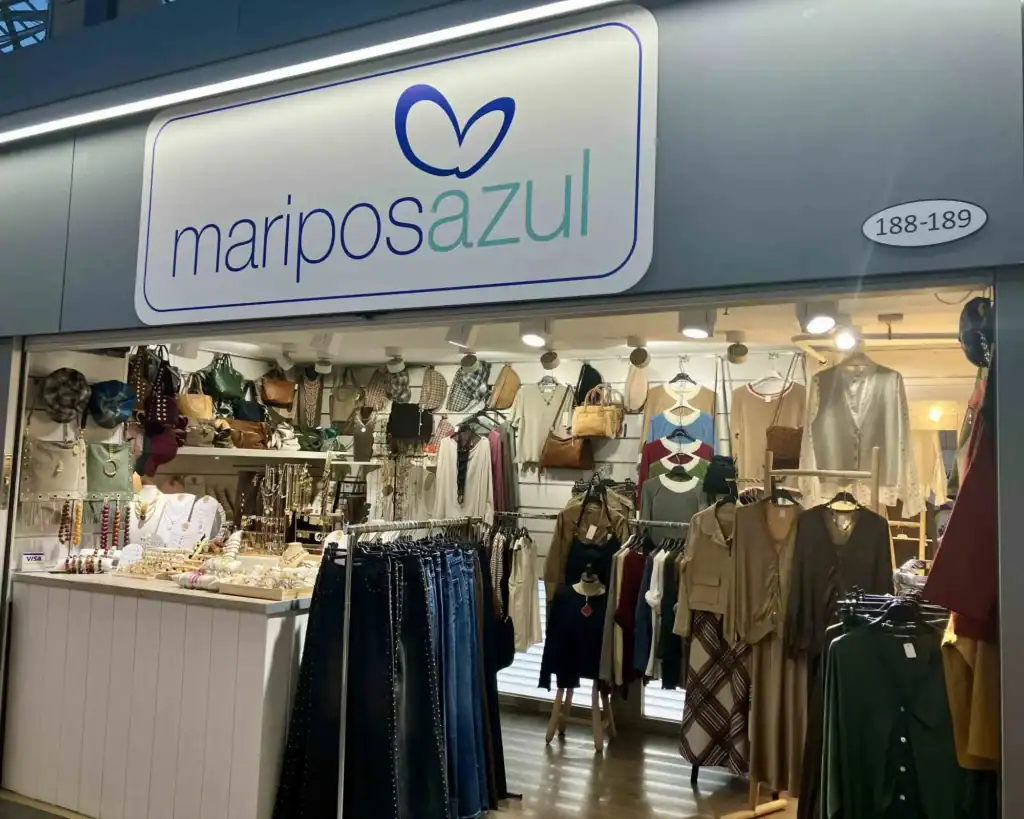 Tienda Mariposazul en paradas 188-189 del Mercat Sant Antoni Barcelona, con escaparate iluminado que exhibe moda femenina, accesorios, bolsos y joyería. El local destaca por su diseño moderno y variedad de estilos.